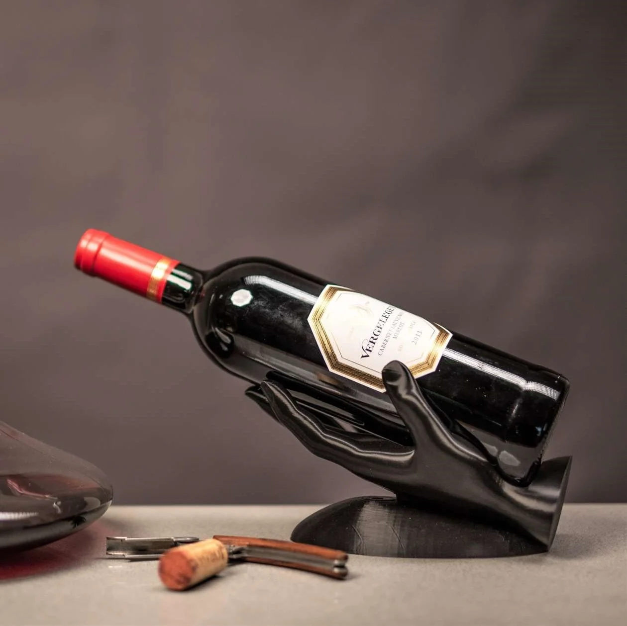 Porte-bouteille en forme de main finition noir mat tenant une bouteille de vin rouge